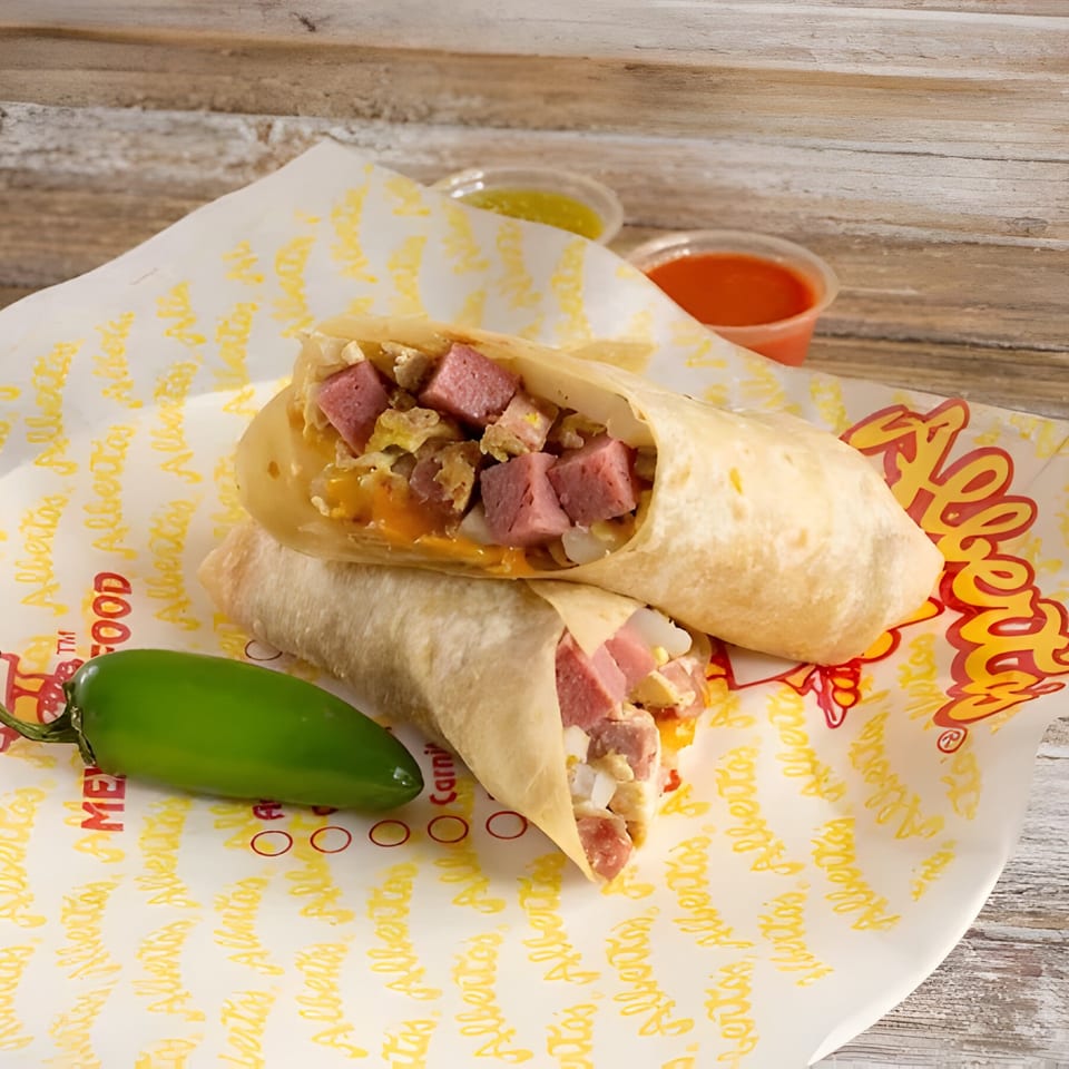 Two Alberto's burritos filled with meat and cheese, a jalapeño, and two sauce cups on branded paper.